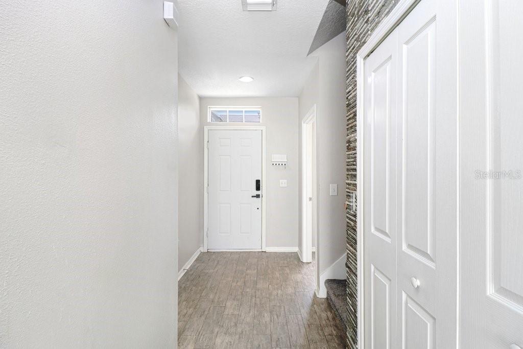 An entryway with light-colored walls, wood-look tile flooring, a white front door, and a closet — 9915 NEW PARKE ROAD, TAMPA, FL