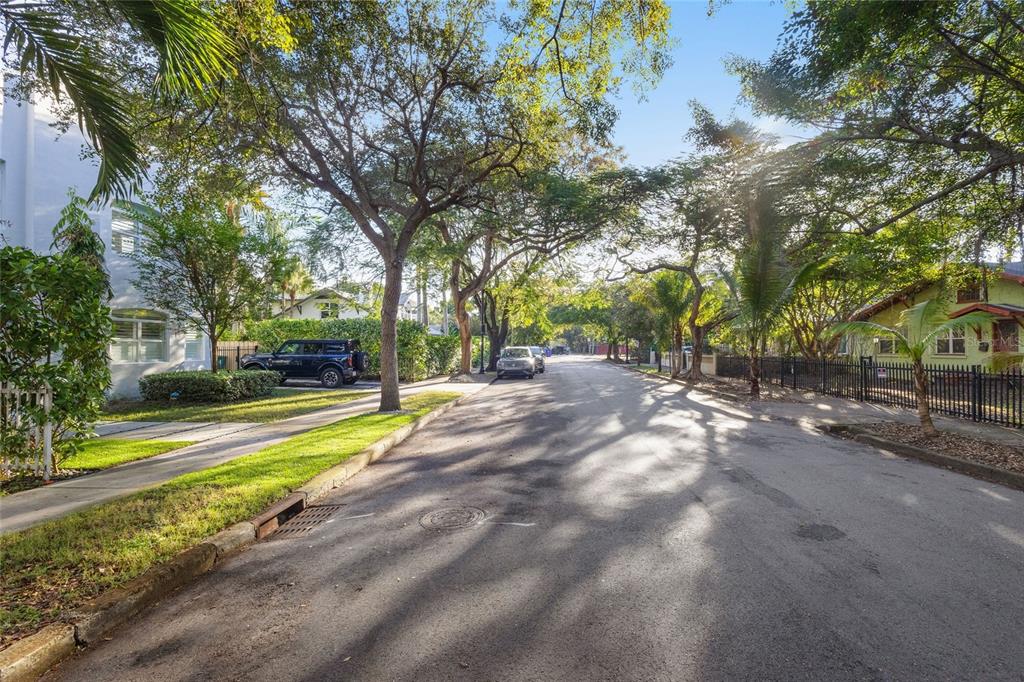 A tree-lined residential street with parked cars and houses on a sunny day — 58 NE 48TH STREET, MIAMI, FL