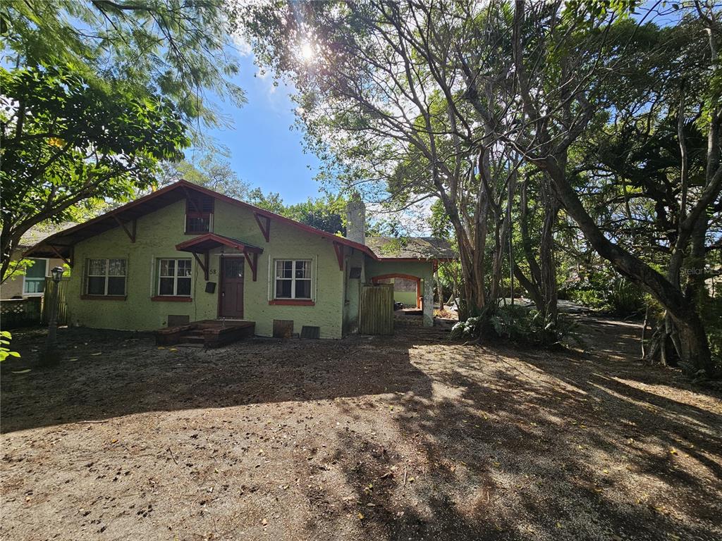 A light green, single-story house with a red-trimmed front entrance sits among mature trees — 58 NE 48TH STREET, MIAMI, FL