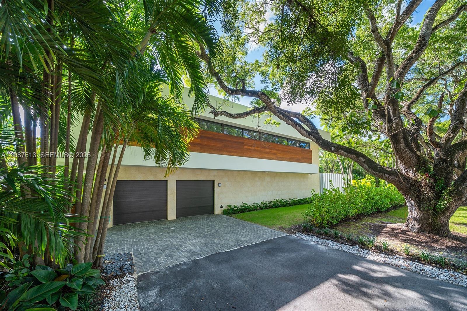 A modern two-story house features a stone base, wood-paneled upper level, and two garage doors — 4041 S Le Jeune Rd, Miami FL 33146, MIAMI, FL