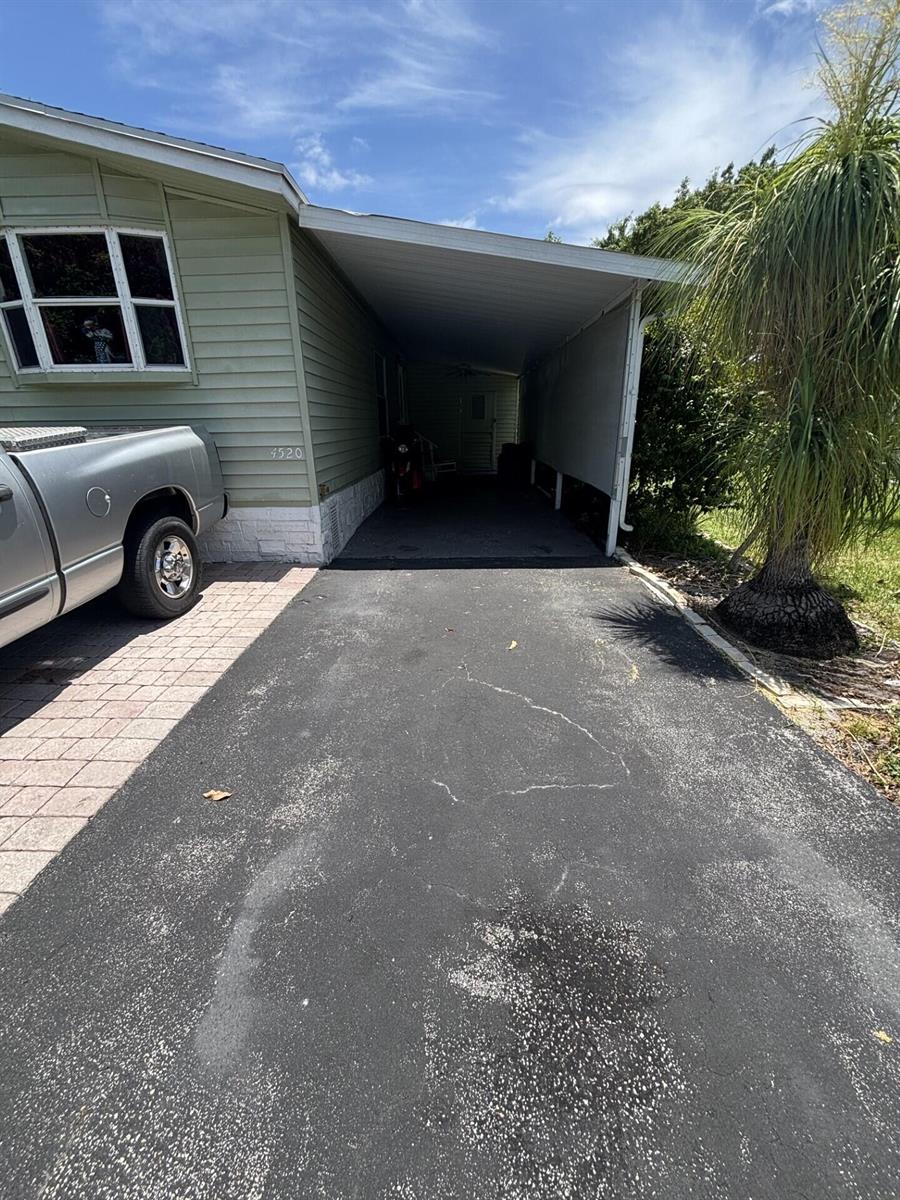 A paved driveway leads to a covered carport beside a light green manufactured home — 4520 NW 68th Place, Coconut Creek FL 33073, COCONUT CREEK, FL