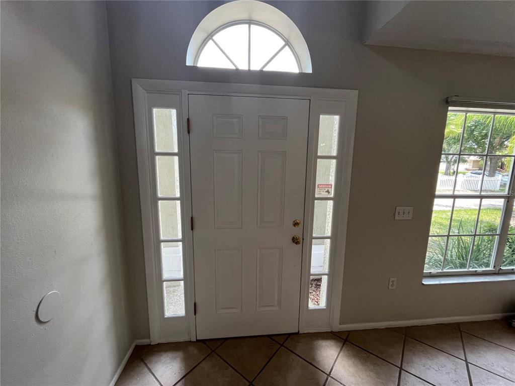 An entryway features a white front door with sidelights, a transom window, and tiled flooring — 820 STONECHAPEL COURT, APOPKA, FL
