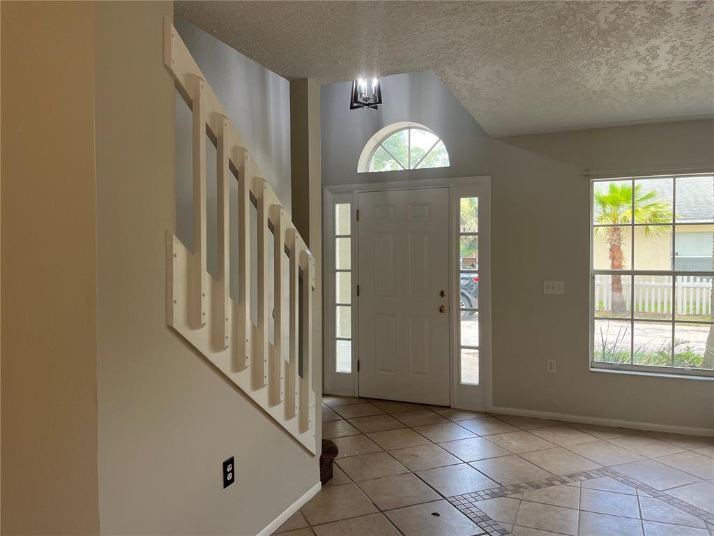 An entryway features a staircase with white railings, tile flooring, and a front door — 820 STONECHAPEL COURT, APOPKA, FL