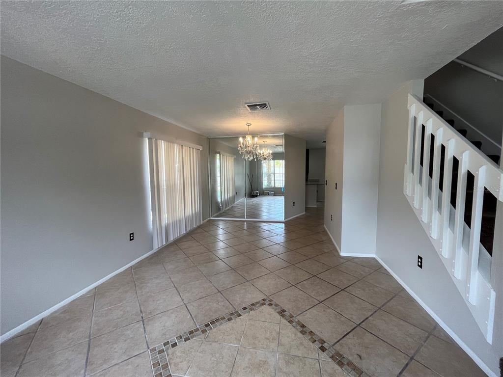 An interior view of a dining area with tiled floors, a mirrored wall, and a staircase — 820 STONECHAPEL COURT, APOPKA, FL