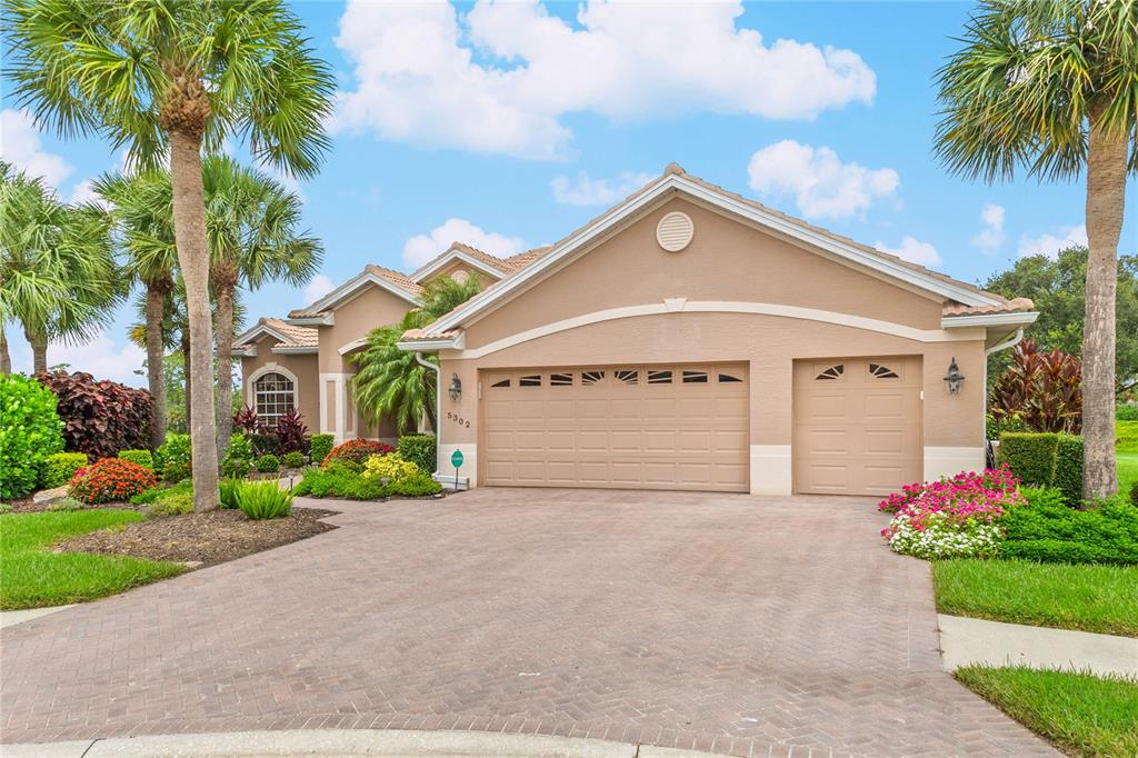 A tan single-story house with a three-car garage and palm trees in the front yard — 5302 WHITE IBIS CT., NORTH PORT, FL