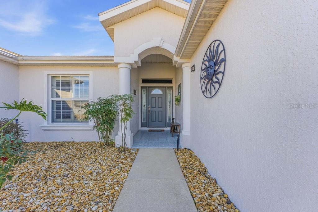 The exterior of a house features a concrete walkway leading to a covered front entrance — 1338 SW 161ST PLACE, OCALA, FL