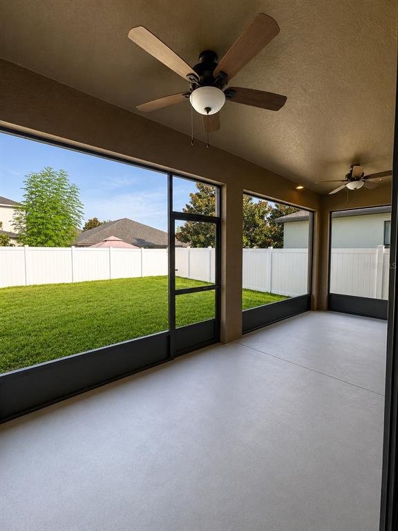 A covered screened-in patio features a concrete floor, two ceiling fans, and a fenced backyard — 10908 WHITTNEY CHASE DRIVE, RIVERVIEW, FL