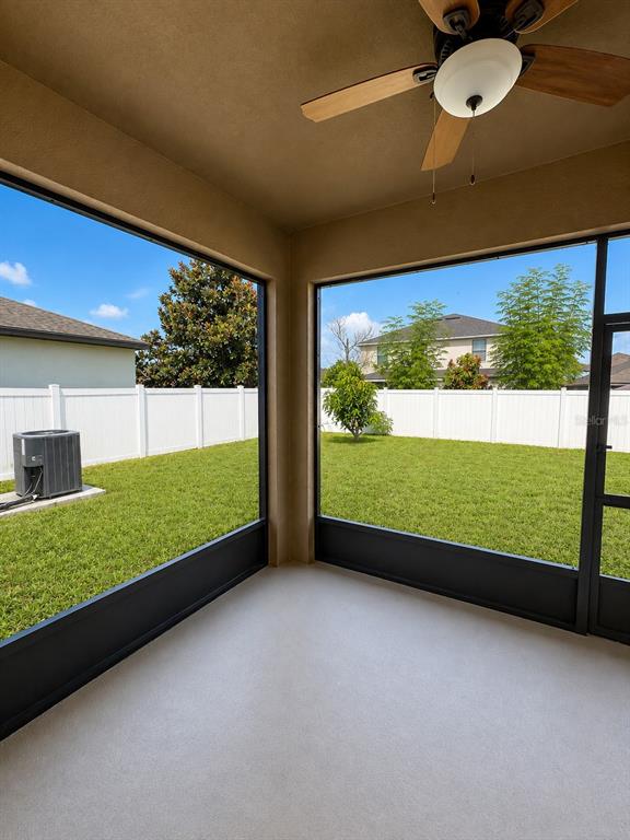 A screened-in patio with a ceiling fan overlooks a fenced backyard and neighboring houses — 10908 WHITTNEY CHASE DRIVE, RIVERVIEW, FL
