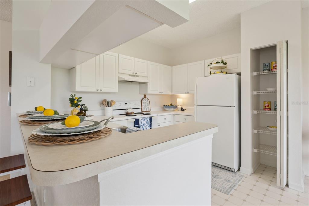 A kitchen features white cabinets, a white refrigerator, a breakfast bar, and an open pantry — 426 ARBOR LAKES UNIT 426, SANFORD, FL