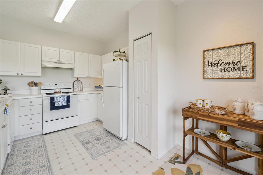 A kitchen features white cabinets, white appliances, a pantry closet, and a wooden console table — 426 ARBOR LAKES UNIT 426, SANFORD, FL