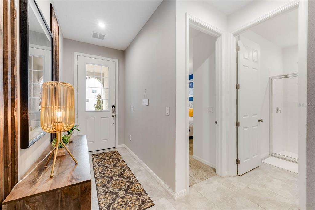 A bright entryway features a wood console table, a patterned runner, and a tiled floor — 8943 AMELIA DOWNS TRAIL, KISSIMMEE, FL