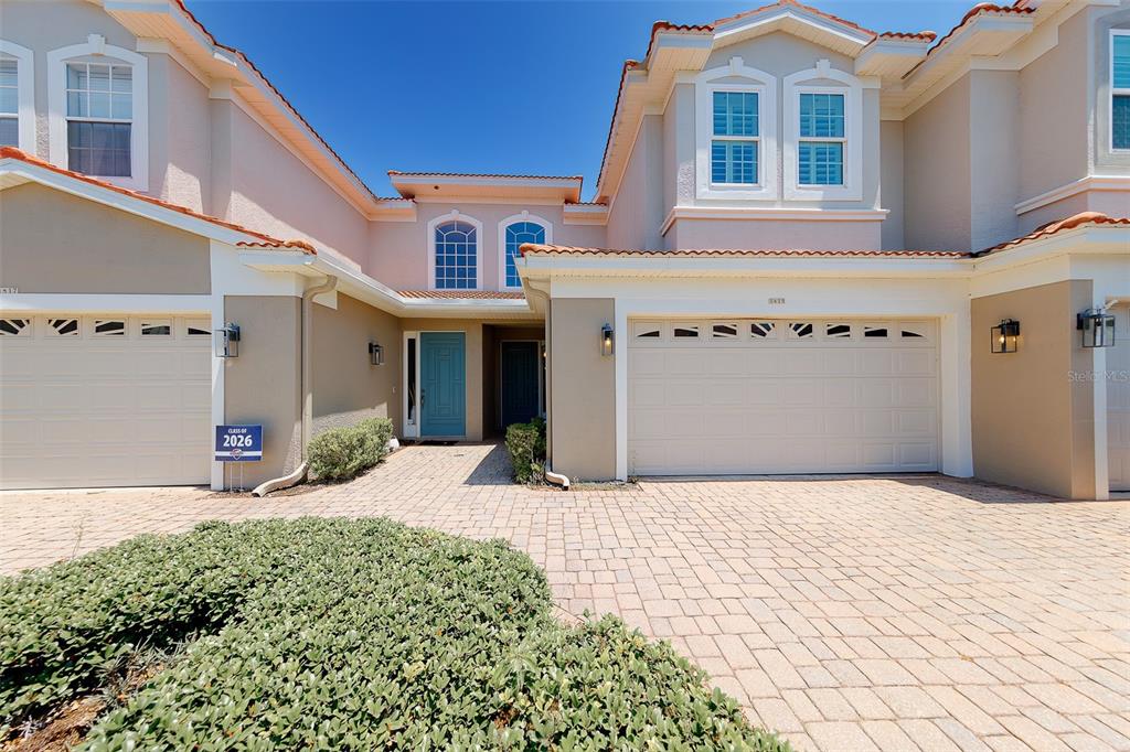 A two-story suburban home features a paved driveway, two garage doors, and a teal front door — 1415 TESSANO PLACE, PALM HARBOR, FL