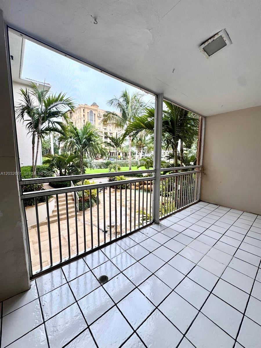 A tiled balcony features a screened enclosure overlooking a courtyard with palm trees and buildings — 2501 S Ocean Blvd # 1040, Boca Raton FL 33432, BOCA RATON, FL