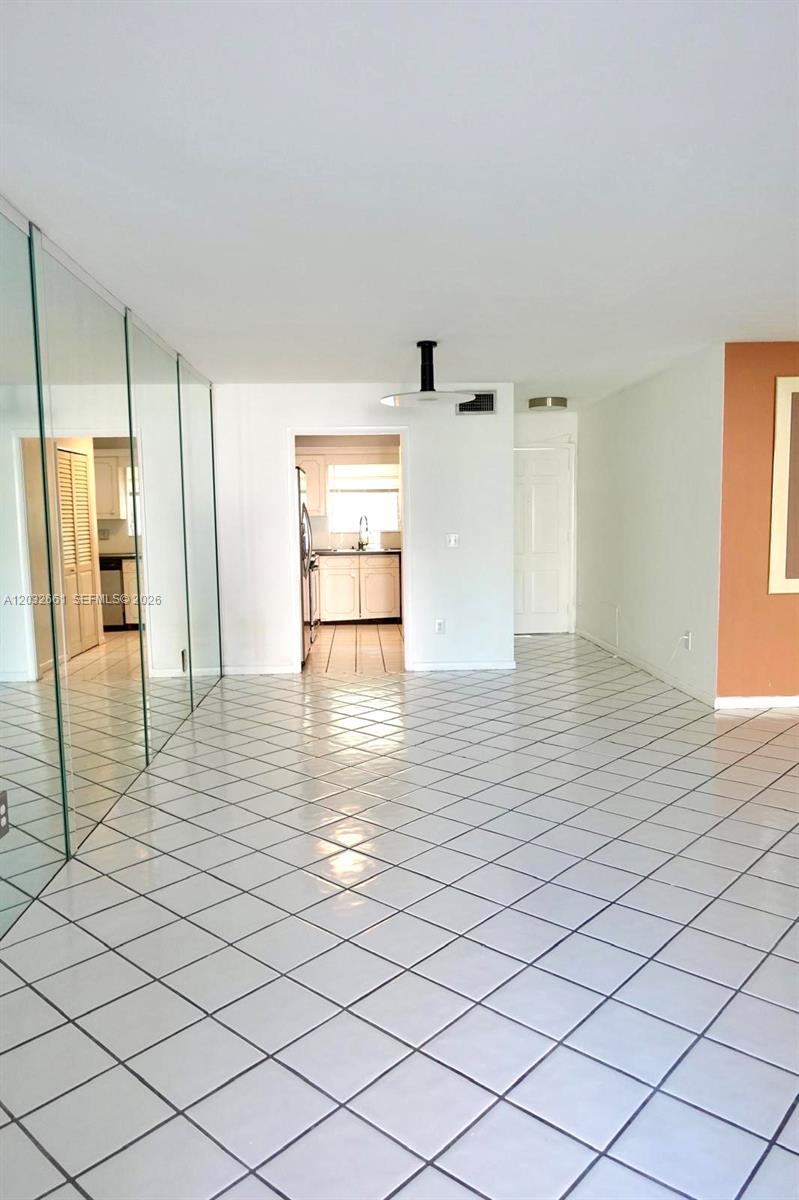 A tiled room features a mirrored wall and an open doorway leading to a kitchen — 2501 S Ocean Blvd # 1040, Boca Raton FL 33432, BOCA RATON, FL