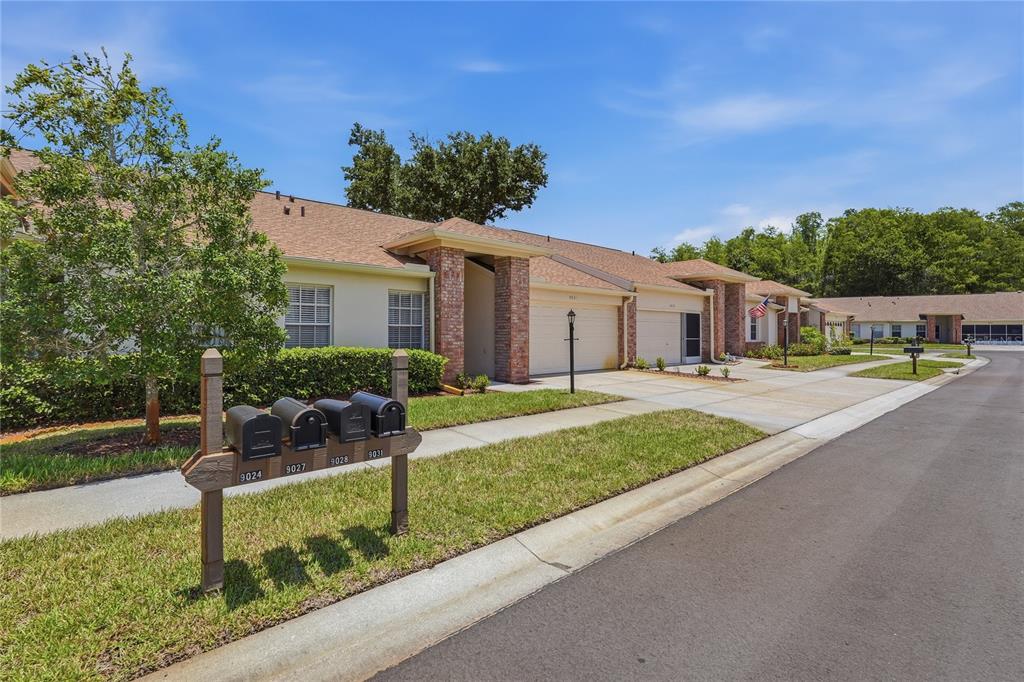 A row of single-story residential units with attached garages and a cluster of mailboxes — 9031 WARWICK LANE UNIT 9031, NEW PORT RICHEY, FL
