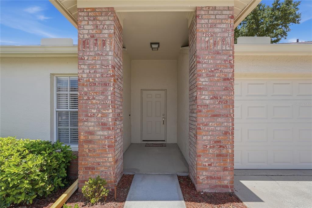 The front entrance features a concrete walkway leading to a door between two brick pillars — 9031 WARWICK LANE UNIT 9031, NEW PORT RICHEY, FL