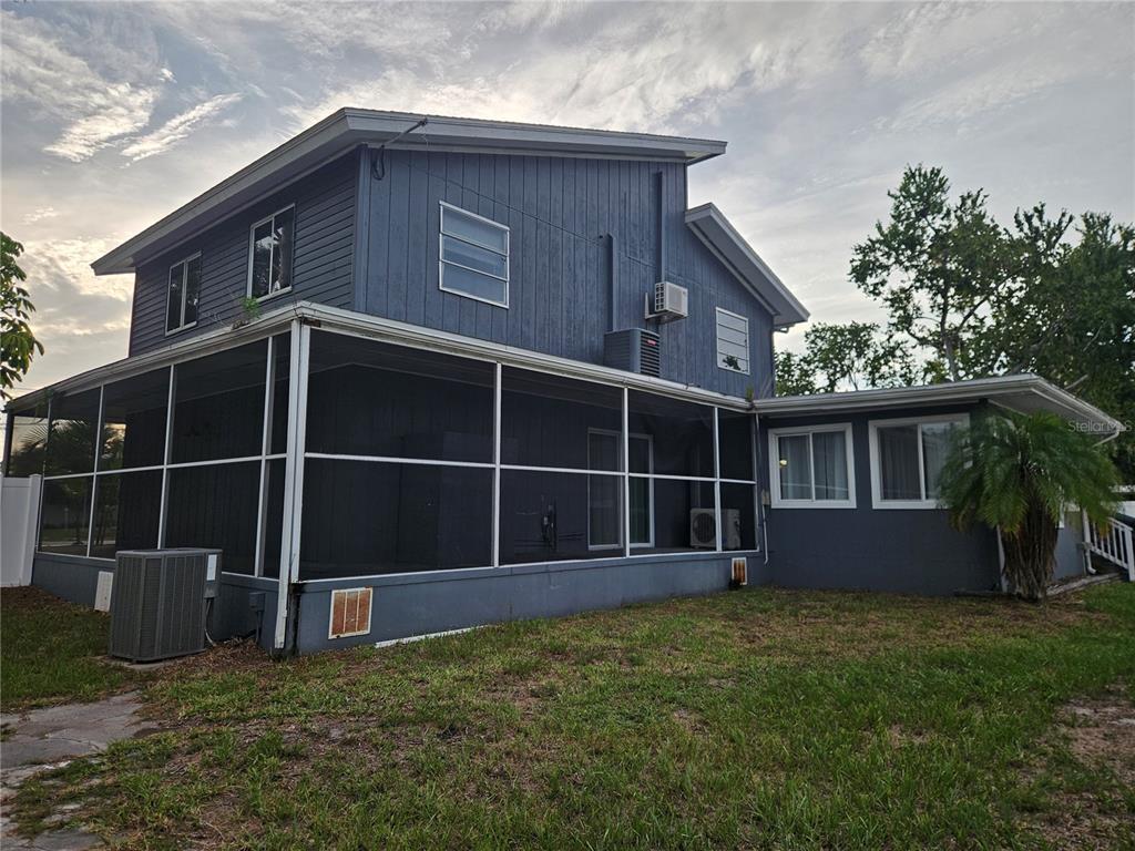 The exterior of a two-story blue house features a large screened-in porch and lawn — 2321 INGRAM AVENUE, SARASOTA, FL