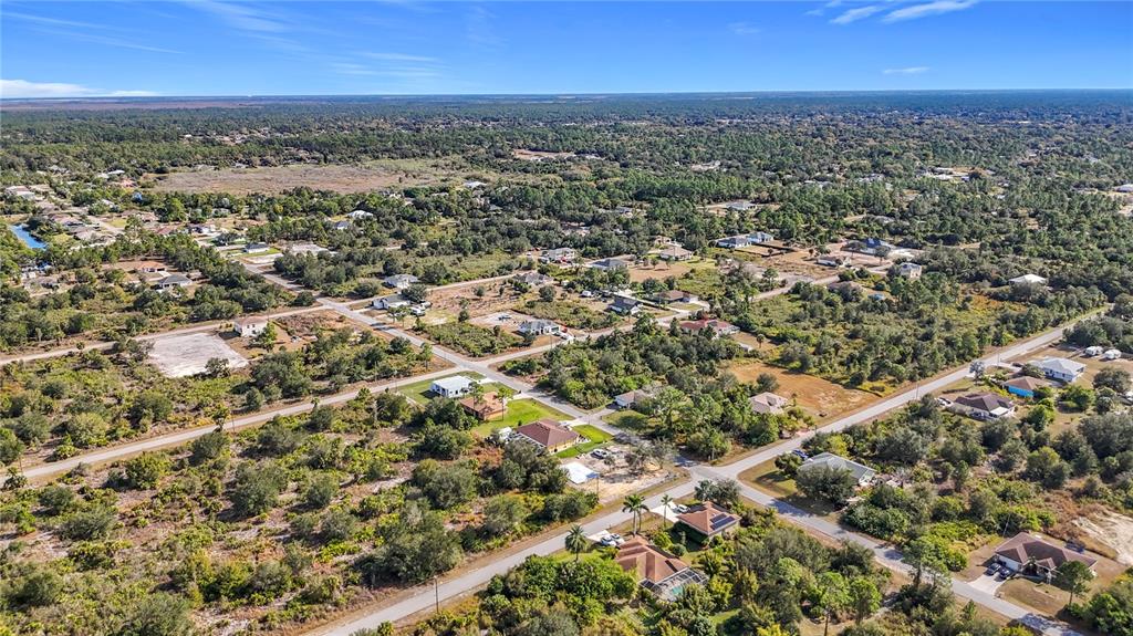 An aerial view shows scattered houses situated among dense trees and undeveloped land — 904 LAKE AVENUE, LEHIGH ACRES, FL