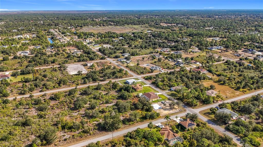 An aerial view shows scattered houses and vacant lots surrounded by dense trees and roads — 904 LAKE AVENUE, LEHIGH ACRES, FL