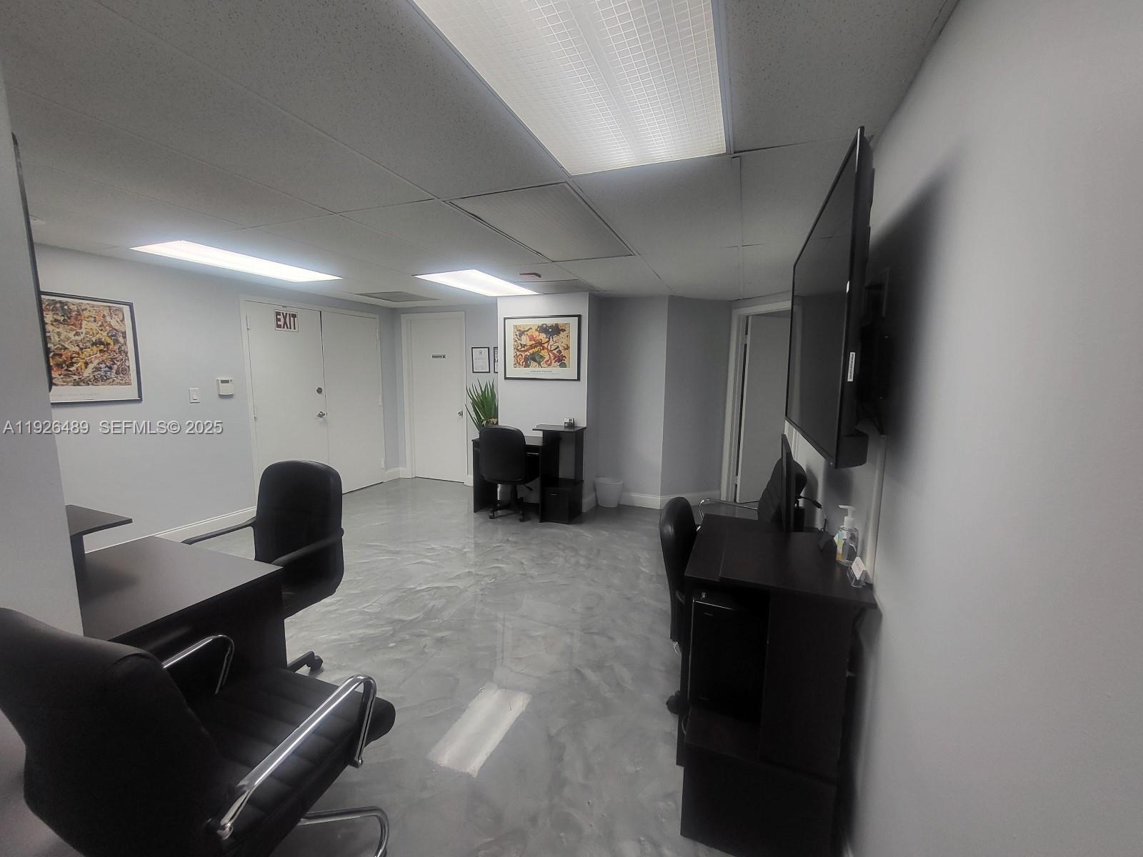 An office space features dark furniture, a wall-mounted television, and a polished gray floor — 13499 Biscayne Blvd, North Miami FL 33181, NORTH MIAMI, FL