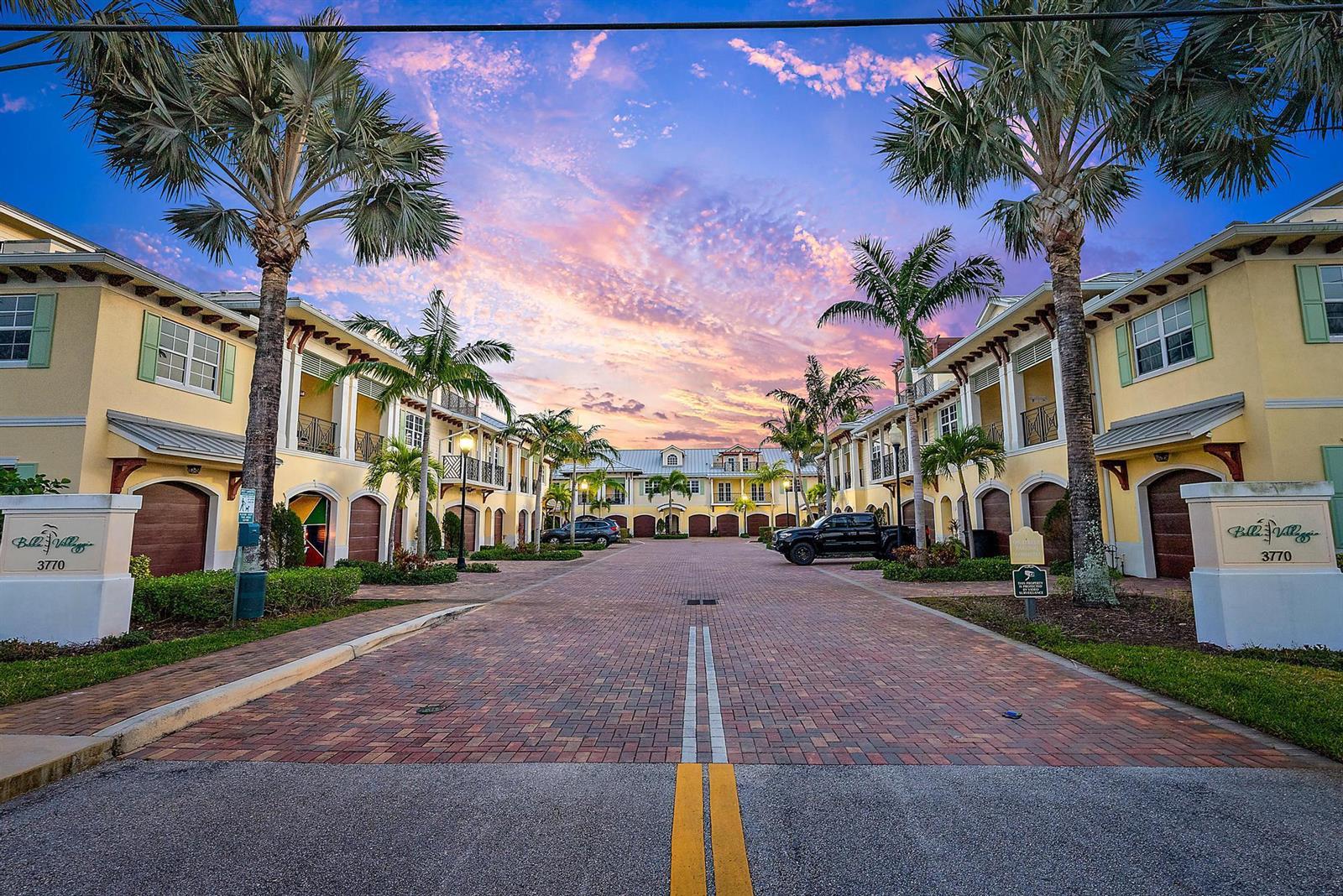 A paved driveway leads between two rows of yellow townhomes lined with palm trees — 3770 County Line Road # A1, Tequesta FL 33469, TEQUESTA, FL