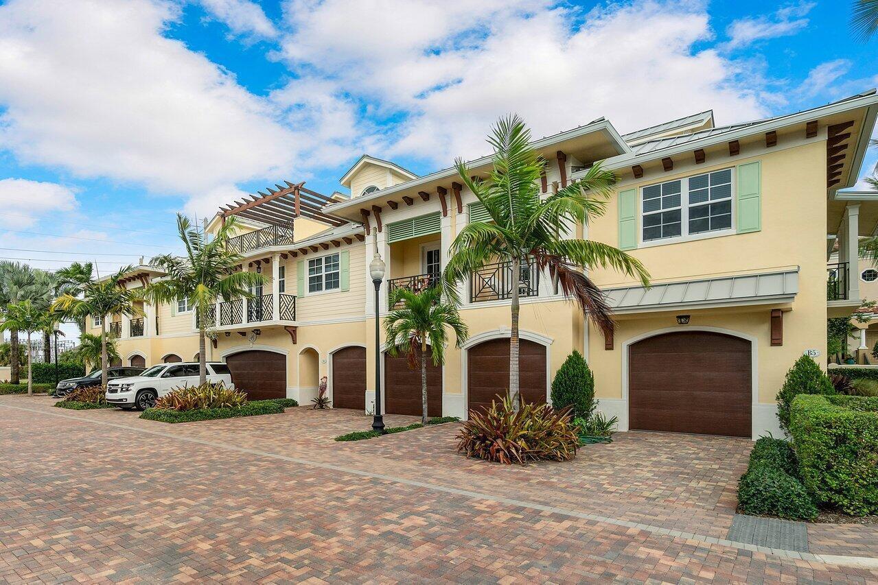 A multi-story yellow townhouse complex with brown garage doors and a brick-paved driveway — 3770 County Line Road # A1, Tequesta FL 33469, TEQUESTA, FL