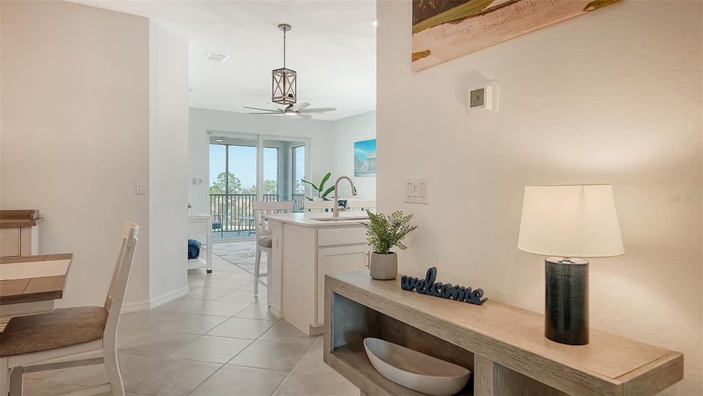 A view from a hallway looking into a kitchen with an island and dining area — 12280 WELLEN GOLF STREET UNIT 308, VENICE, FL