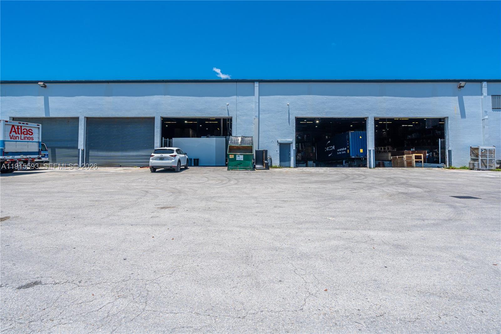 An exterior view of a warehouse building with multiple loading bays and a paved lot — 3353 NW 74th Ave, Miami FL 33122, MIAMI, FL
