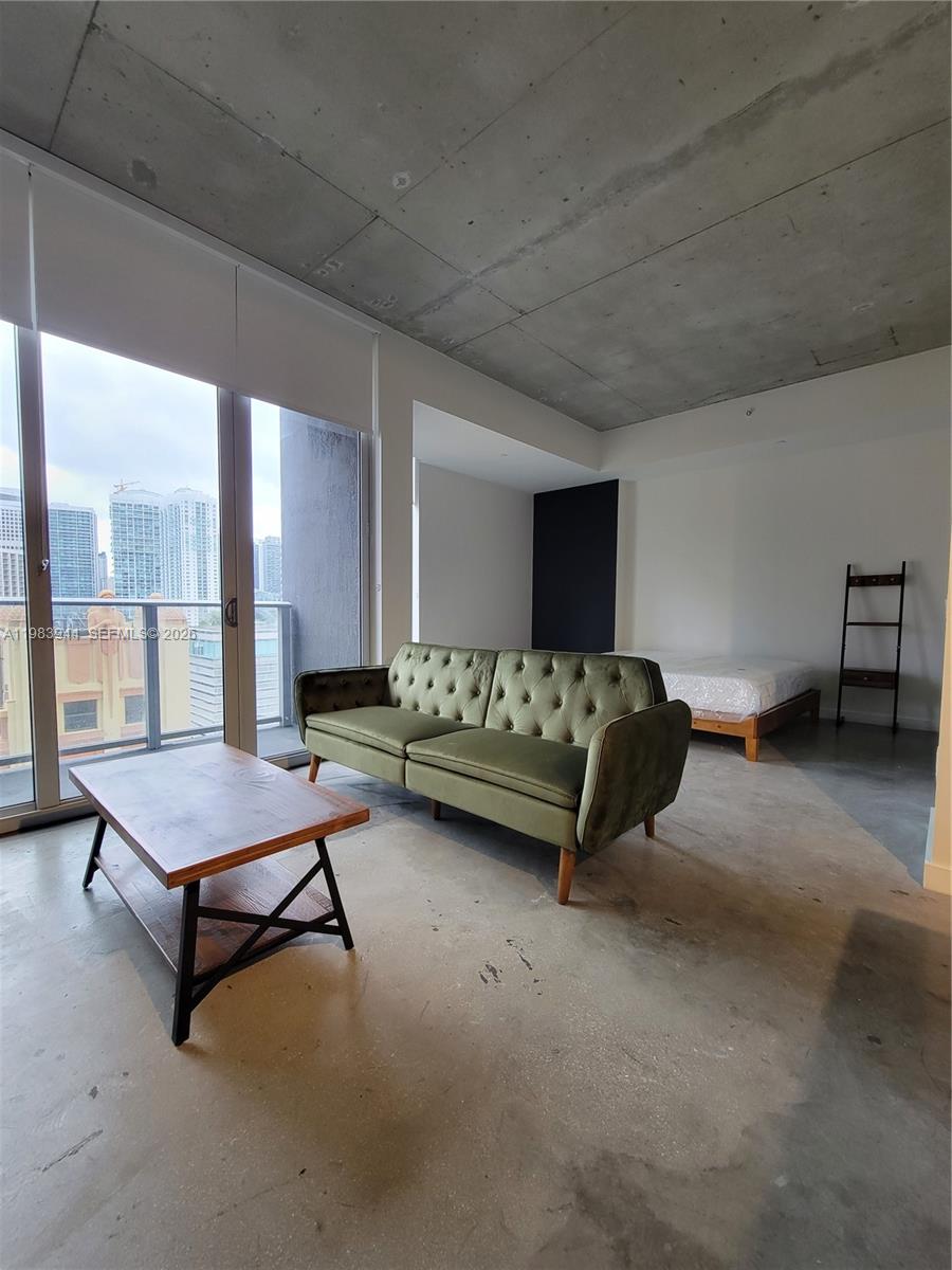 A studio apartment features a green tufted sofa, a coffee table, and a bed — 151 SE 1st St # 1507, Miami FL 33131, MIAMI, FL