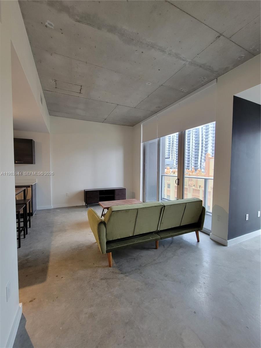 A living room features a green sofa, concrete floors, an exposed ceiling, and a balcony — 151 SE 1st St # 1507, Miami FL 33131, MIAMI, FL