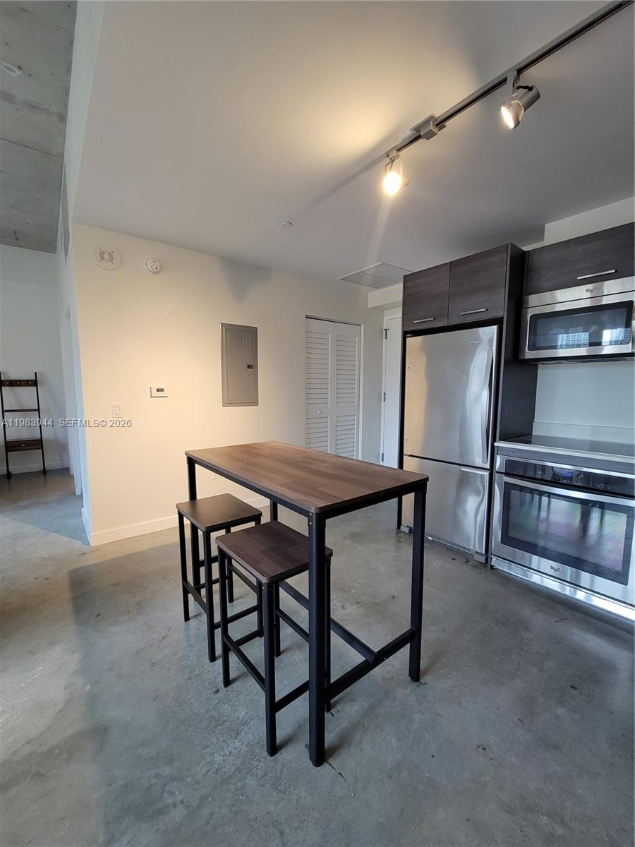 A kitchen features stainless steel appliances, dark cabinetry, a wooden table, and concrete flooring — 151 SE 1st St # 1507, Miami FL 33131, MIAMI, FL