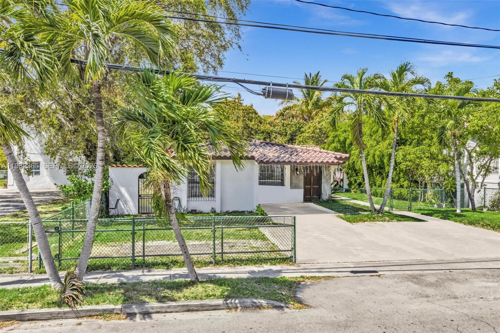 A single-story white house with a tiled roof sits behind a green chain-link fence — 1010 SW 14th Ave, Miami FL 33135, MIAMI, FL