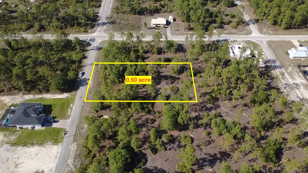 An aerial view shows a rectangular, wooded 0.50-acre vacant lot outlined in yellow — 920 LOUIS AVENUE, LEHIGH ACRES, FL