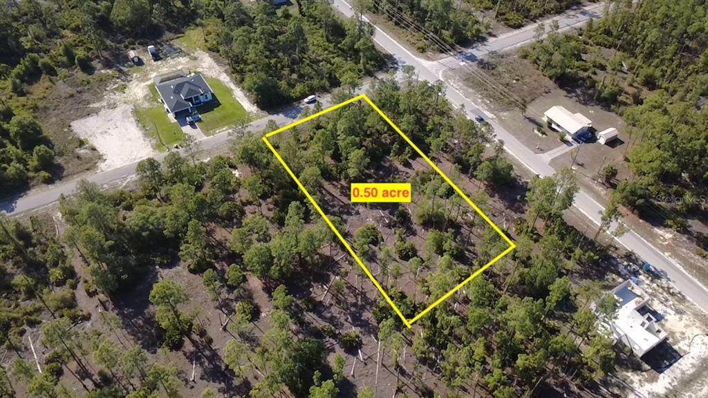 An aerial view shows a rectangular, wooded 0.50-acre vacant lot outlined in yellow — 920 LOUIS AVENUE, LEHIGH ACRES, FL