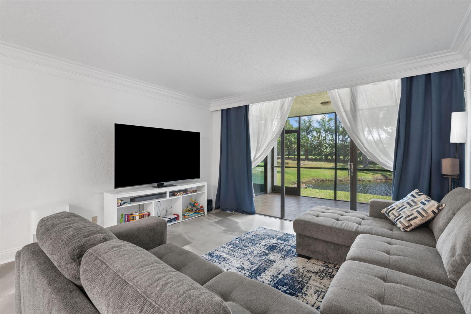 A living room features a grey sectional sofa, a television on a white stand, and sliding doors — 6562 Boca Del Mar Drive # 124, Boca Raton FL 33433, BOCA RATON, FL