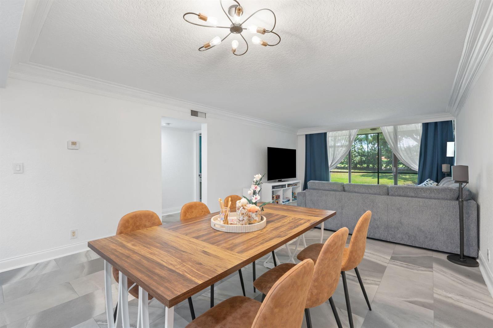 A dining area with a wooden table and chairs sits before a living room — 6562 Boca Del Mar Drive # 124, Boca Raton FL 33433, BOCA RATON, FL