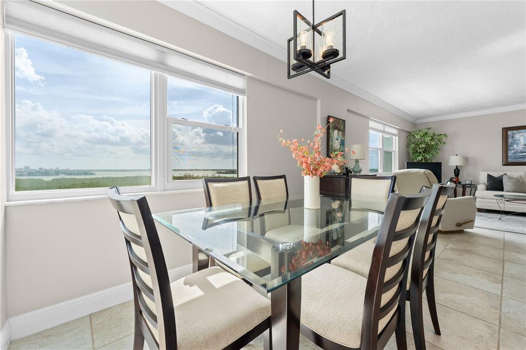A dining area with a glass table, dark chairs, and a large window overlooking water — 1700 BENJAMIN FRANKLIN DRIVE UNIT 10F, SARASOTA, FL
