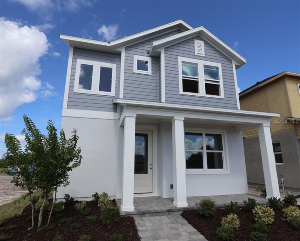 A modern kitchen features white cabinetry, a central island, stainless steel appliances, and wood flooring — 5640 SAVANNA VALLEY TRAIL, ST CLOUD, FL