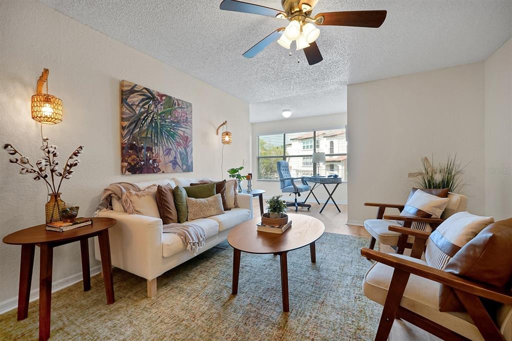 A living room features a white sofa, two wooden armchairs, a coffee table, and a desk — 5156 CONROY ROAD UNIT 26, ORLANDO, FL