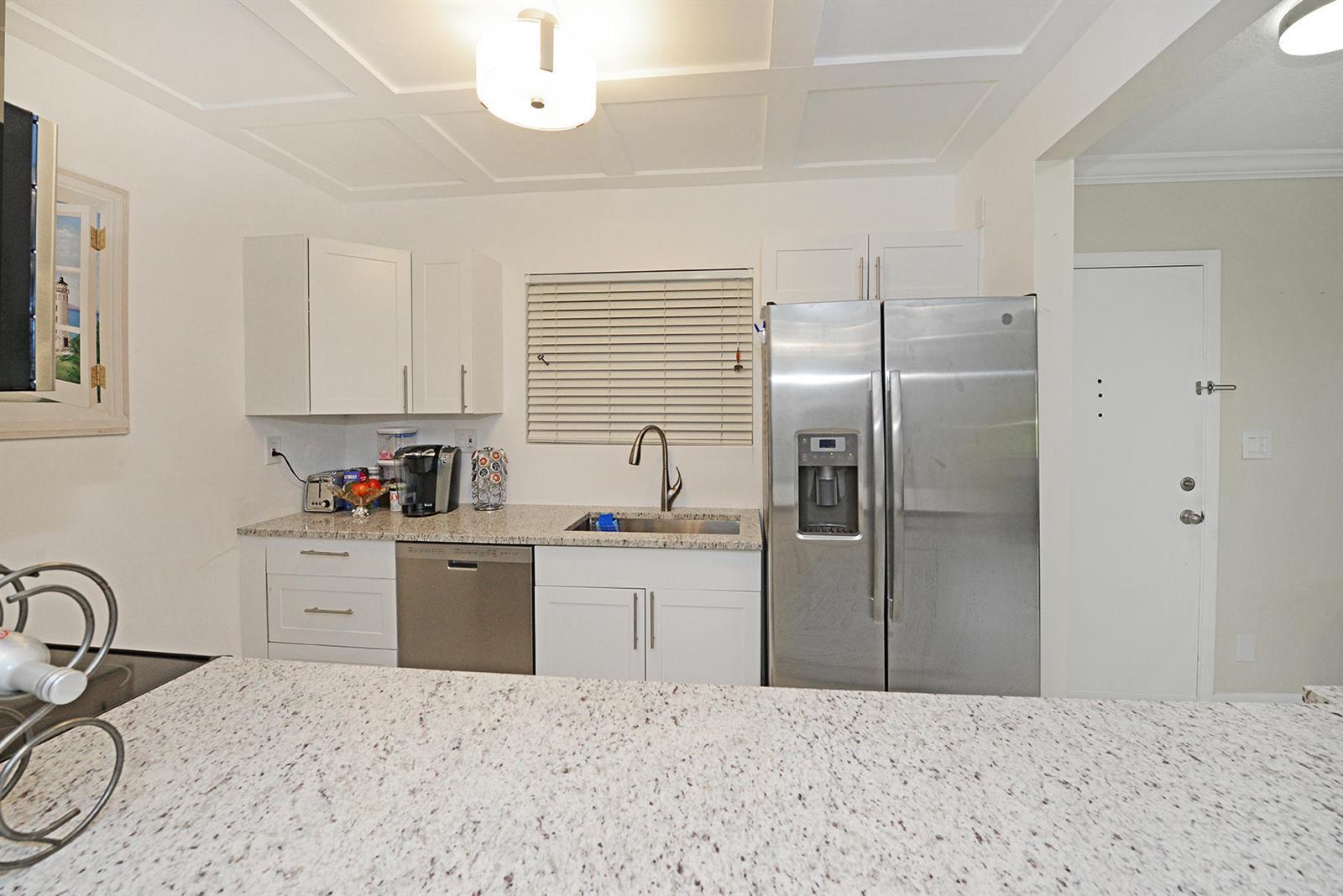 A kitchen features white cabinets, granite countertops, stainless steel appliances, and a coffered ceiling — 297 Deer Creek Boulevard # 1302, Deerfield Beach FL 33442, DEERFIELD BEACH, FL