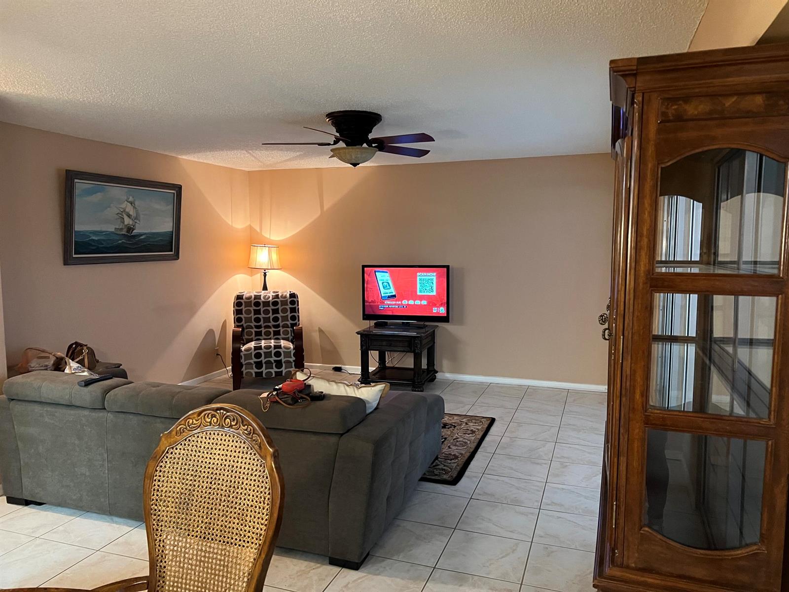 A living room features a gray sectional sofa, a patterned armchair, and a television — 203 Suffolk, Boca Raton FL 33434, BOCA RATON, FL