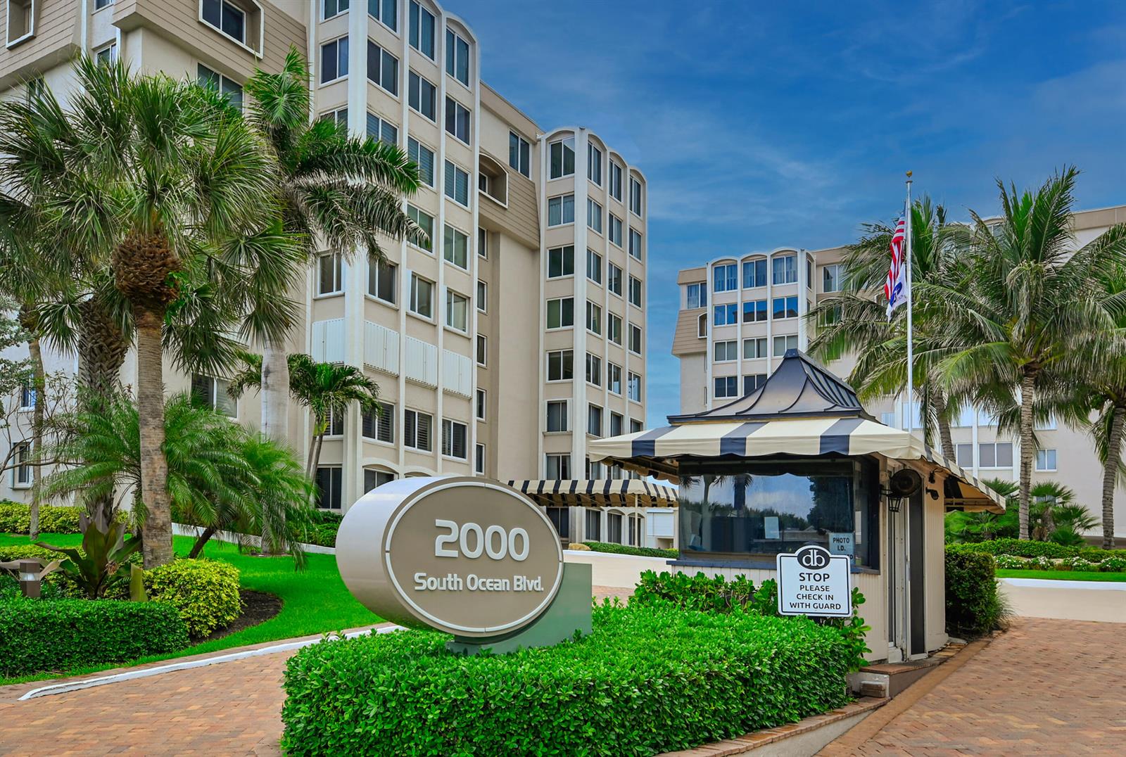 The exterior of a multi-story apartment building features a security gatehouse and a circular sign — 2000 S Ocean Boulevard # 208, Delray Beach FL 33483, DELRAY BEACH, FL