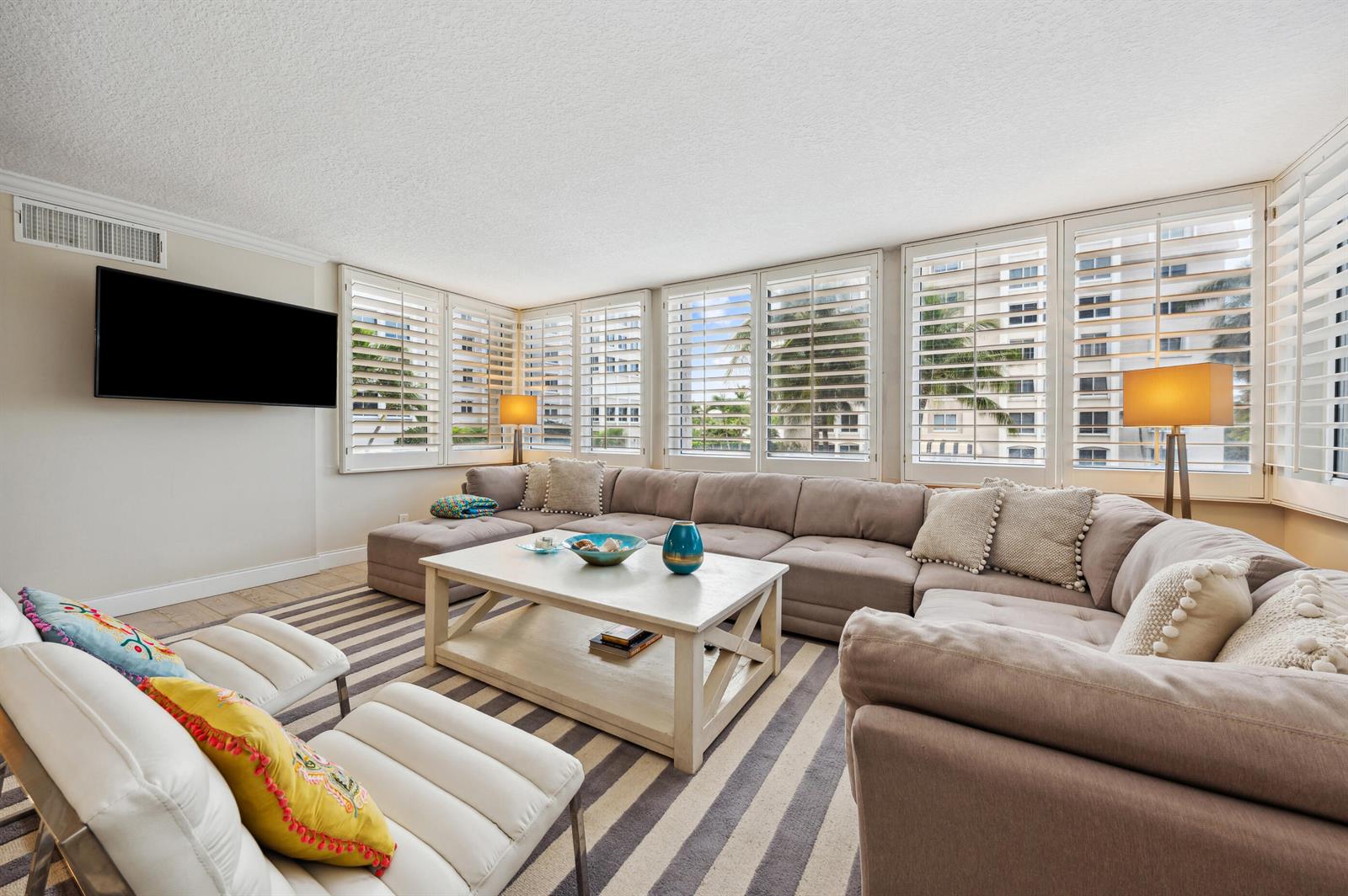 A living room features a large sectional sofa, a coffee table, and windows with shutters — 2000 S Ocean Boulevard # 208, Delray Beach FL 33483, DELRAY BEACH, FL