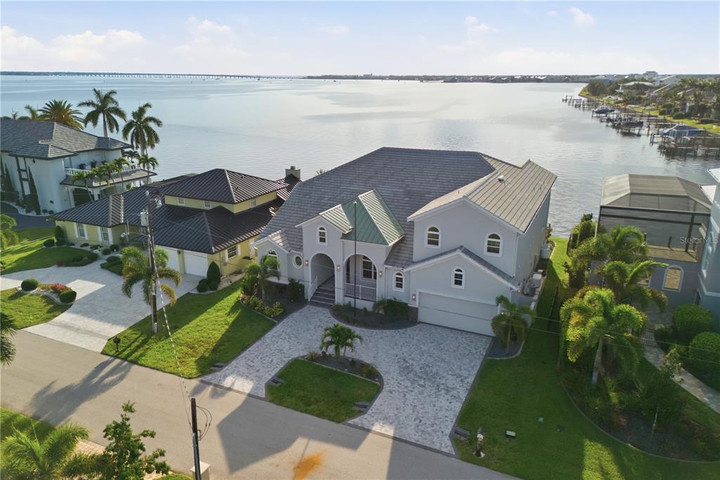 An aerial view shows a two-story waterfront house with a paved driveway and palm trees — 2139 PALM TREE DRIVE, PUNTA GORDA, FL