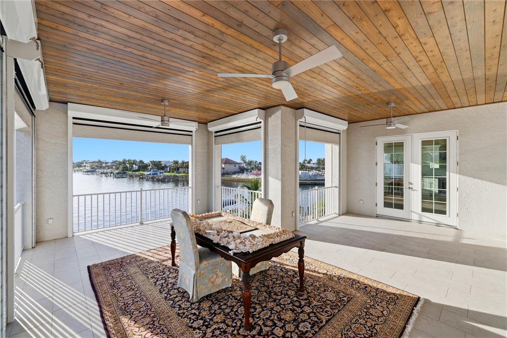 A covered patio features a wood-paneled ceiling, ceiling fans, and views of a waterfront canal — 2139 PALM TREE DRIVE, PUNTA GORDA, FL