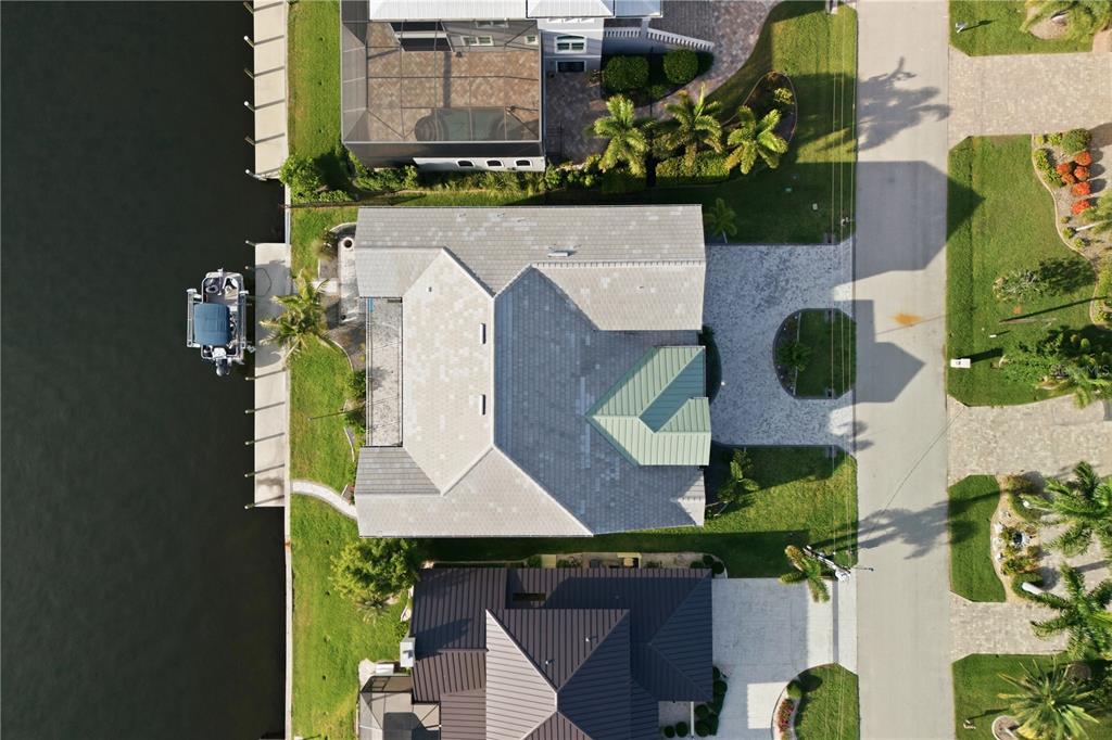 An aerial view shows a waterfront house with a gray roof, green accent roof, and boat dock — 2139 PALM TREE DRIVE, PUNTA GORDA, FL