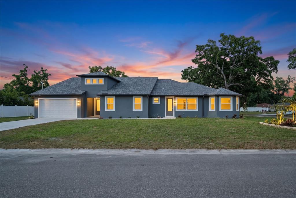 A single-story gray house with a two-car garage and a large front lawn at sunset — 6401 FELICE AVENUE, TAMPA, FL