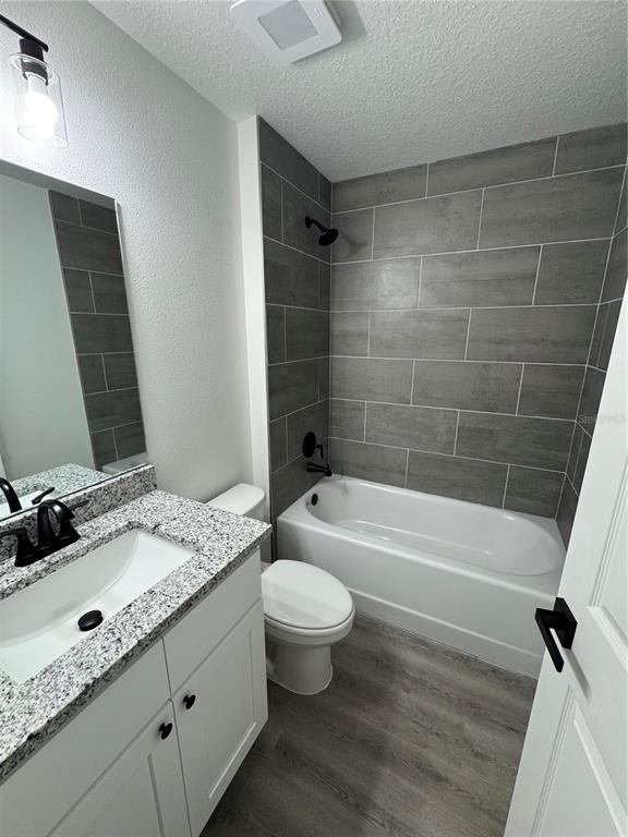 A bathroom features a white vanity with granite countertop, a toilet, and a tiled tub-shower — 15045 SE 61 COURT, SUMMERFIELD, FL
