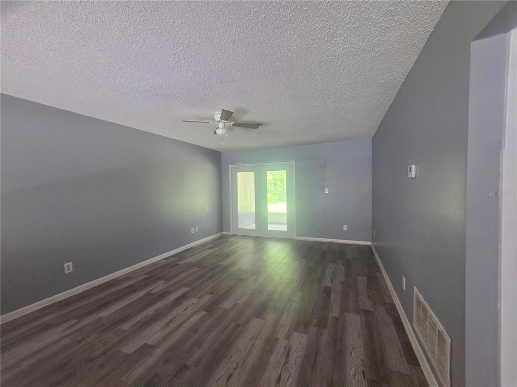 An empty room with gray walls, wood-look flooring, a ceiling fan, and glass patio doors — 1316 MARKHAM AVENUE UNIT B, SPRING HILL, FL