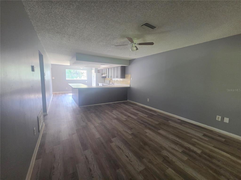 An open-concept living area features gray walls, wood-look flooring, and a kitchen with a breakfast bar — 1316 MARKHAM AVENUE UNIT B, SPRING HILL, FL
